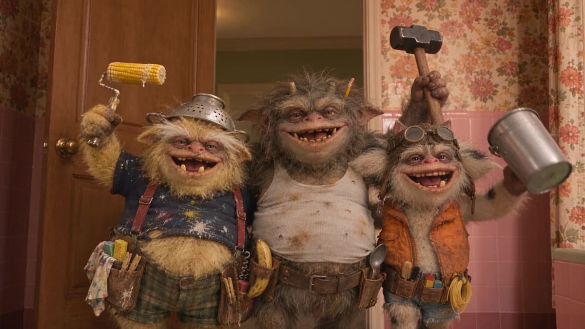 Tres duendes contratistas sonriendo en una puerta, con un rodillo, un martillo y una lata.